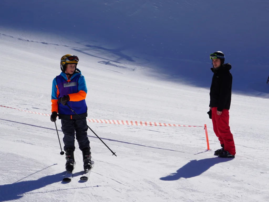Zwei Skifahrende auf der Piste an der Absperrung.